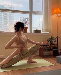 a woman practices yoga in front of a window