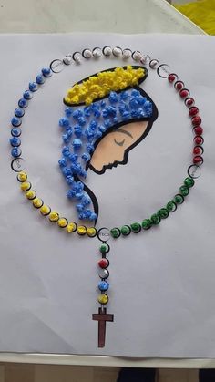 a paper with beads and an image of a woman's head on it, hanging from a cross