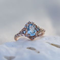 an aqua and white diamond ring sitting on top of a rock