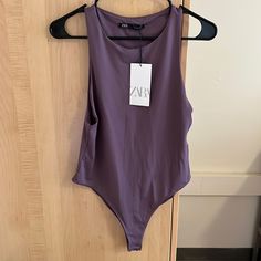 a purple one piece swimsuit hanging on a wooden door