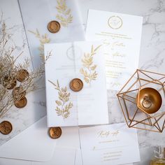 the wedding stationery is laid out on top of each other, with gold coins