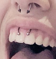 an open mouth with two piercings on it