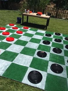 a giant checker board game set up in the yard with red and black discs