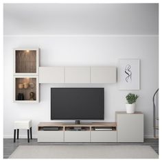 a living room with white furniture and a flat screen tv mounted on the wall above it