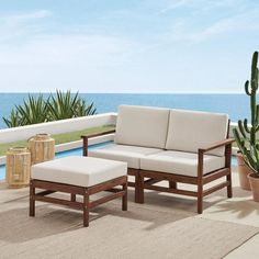 a couch and ottoman sitting on top of a patio next to a pool with water in the background