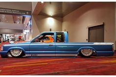 a blue truck parked inside of a building next to a red carpeted flooring