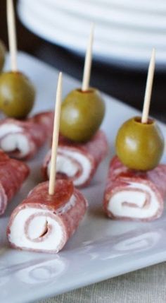 several appetizers are arranged on a plate with toothpicks and olives