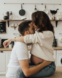 a man and woman sitting on the kitchen counter kissing each other's foreheads