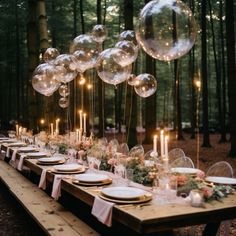 a long table with balloons and plates on it in the middle of a forest filled with trees