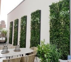 an outdoor dining area with tables and chairs covered in green wall plants on the walls