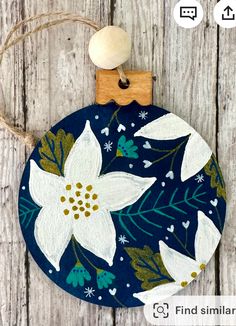 a blue ornament with white flowers is hanging on a wooden background and has a tag that says find similar