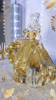 a gold and silver dress on display in front of a glass case with lights around it