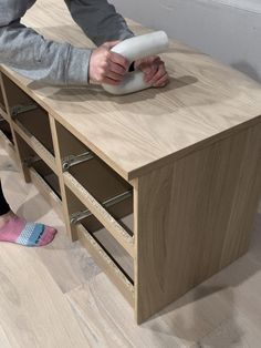 a person using a video game controller on top of a wooden cabinet in a living room