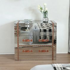 a mirrored chest with flowers in it on the floor