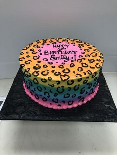 a birthday cake decorated with multicolored leopard print