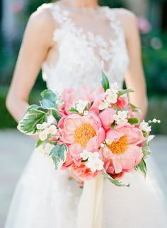 a bride holding a bouquet of pink and white flowers