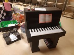 a piano made out of cardboard sitting on top of a table next to other items