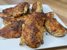 chicken wings on a white plate sitting on a wooden table