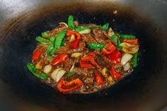 a wok filled with stir fry vegetables and meat