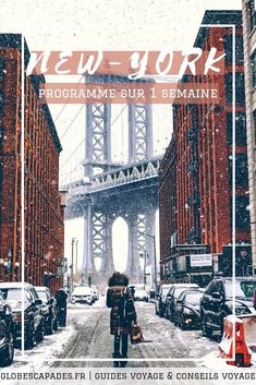 a woman walking down a snow covered street in front of a bridge with the words new york on it