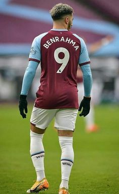 a soccer player is standing on the field with his hands in his pockets and looking down