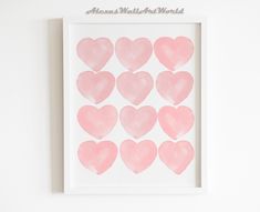 a white frame with pink heart shapes on the wall in front of a white wall