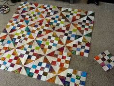 a multicolored quilt laying on the floor next to it's matching pieces