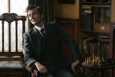 a man sitting in a chair next to a table with some chess pieces on it