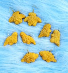 six pieces of fried food are arranged in the shape of fish on a blue fur background