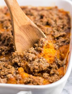 a wooden spoon in a casserole dish filled with meat