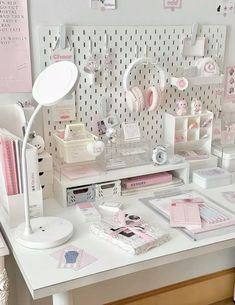 a white desk topped with lots of pink and white items next to a wall mounted clock