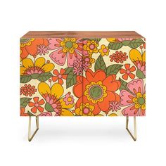 an orange and yellow flowered cabinet with black hairpinks on the legs, against a white background