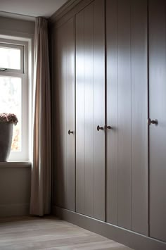 an empty room with some cupboards and a flower pot on the window sill