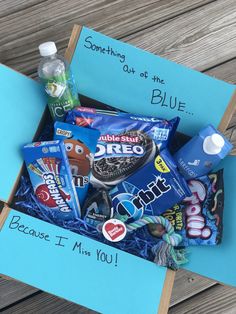 a box filled with snacks and candy on top of a wooden table next to a blue sign