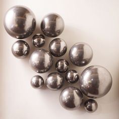 several shiny metal balls are arranged on a white surface, with one being smaller than the other