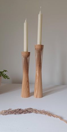 two tall wooden candlesticks sitting next to each other on a white tablecloth