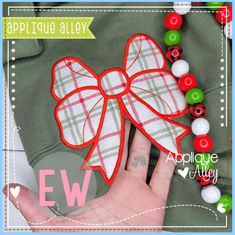 a hand is holding an applique bow on a green jacket with red and white buttons