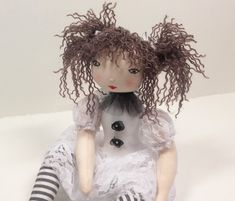 a doll with curly hair sitting on a white surface wearing black and white striped stockings