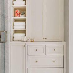 an image of a bathroom setting with white cabinets and marble flooring on the walls