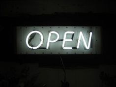 an open sign lit up in the dark with no one around it or someone else