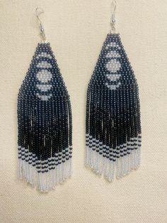 two pairs of black and white beaded earrings with fringes on the bottom, one is