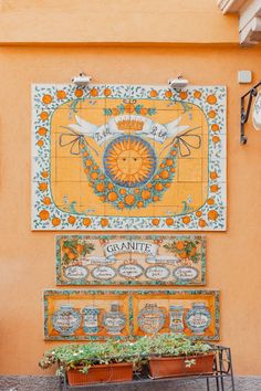 an orange building with colorful tiles on the wall and planters in front of it