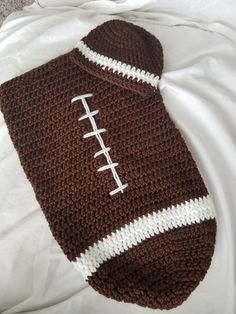 a brown and white crocheted bag with a football on the side sitting on top of a bed