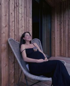 a woman sitting in a chair on a wooden floor next to a wall with wood slats