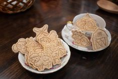 two white plates filled with cookies on top of a wooden table next to each other