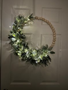 a wreath made out of wood beads and greenery hangs on the front door's wall