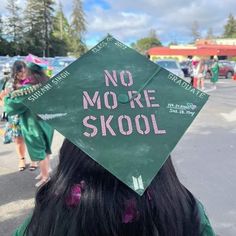 a girl wearing a green graduation cap with the words no more skool written on it