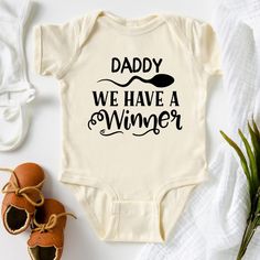 a baby bodysuit with the words daddy we have a winner on it next to some shoes