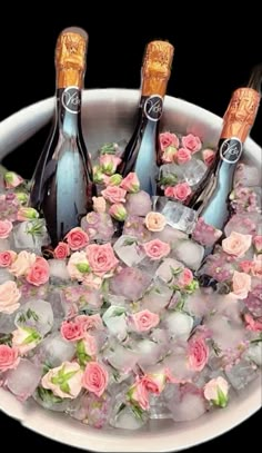 three champagne bottles in ice with pink flowers