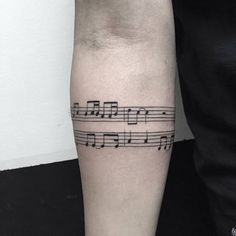 a man's arm with musical notes tattooed on the side of his left arm